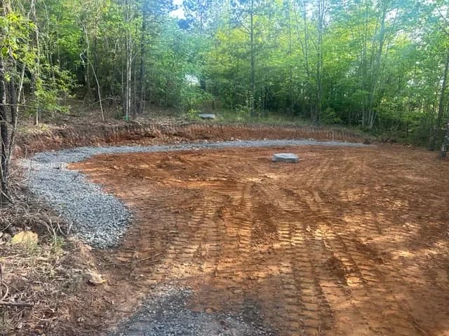 Freshly graded red-dirt building pad cut into wooded acreage in Central Arkansas