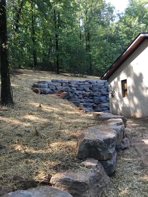 Boulder retaining wall built along a hillside beside a Central Arkansas home